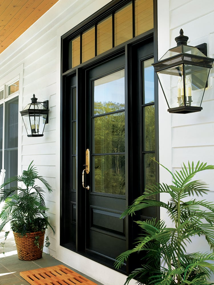 A black front door with a transom window above and sidelights on both sides.