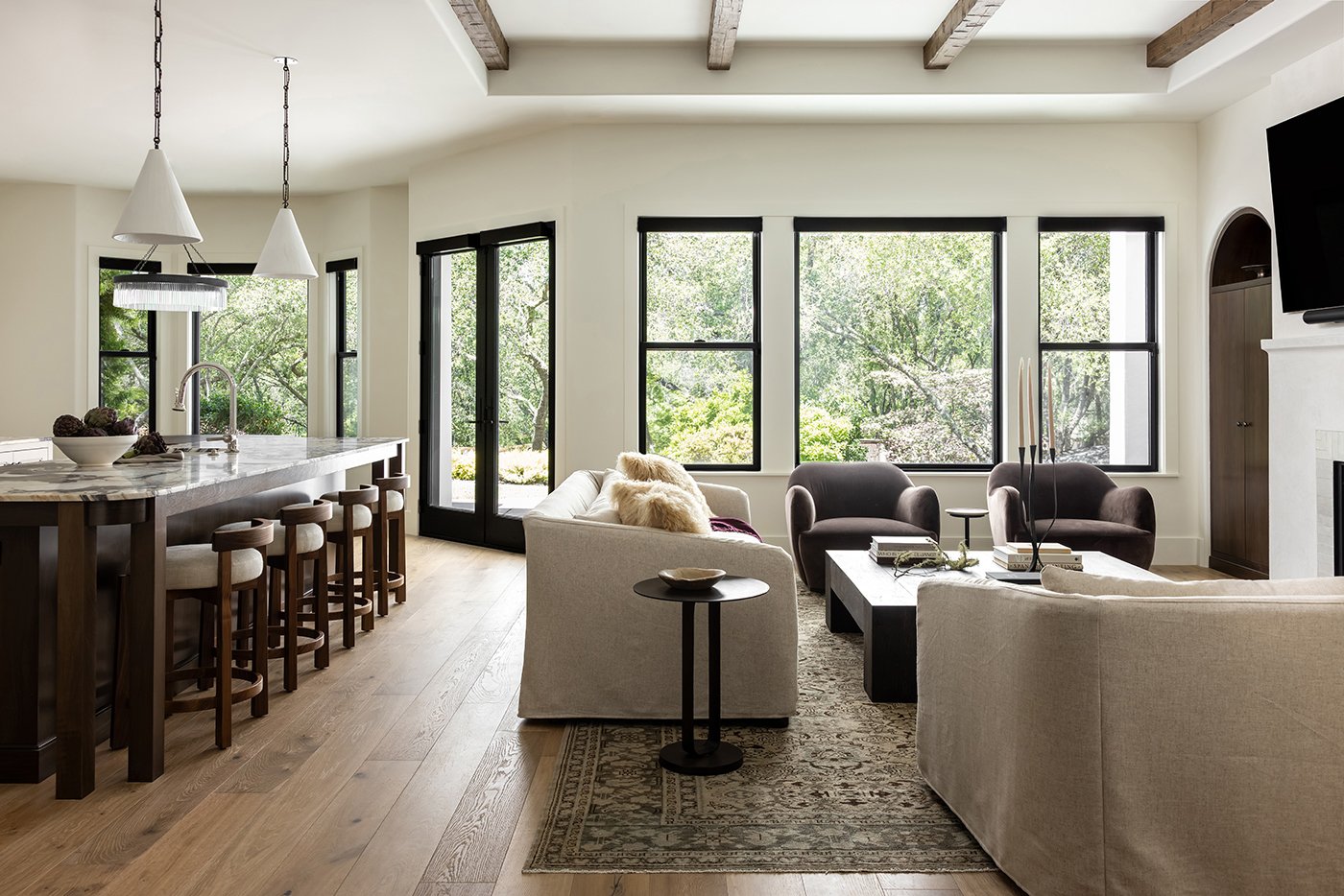 An open-concept space with black windows and black hinged patio doors leading to a patio.