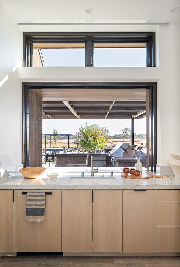A pocketing MultiGlide Pass-Through Window connects this indoor kitchen with the outdoor kitchen area for effortless and efficient entertaining. 