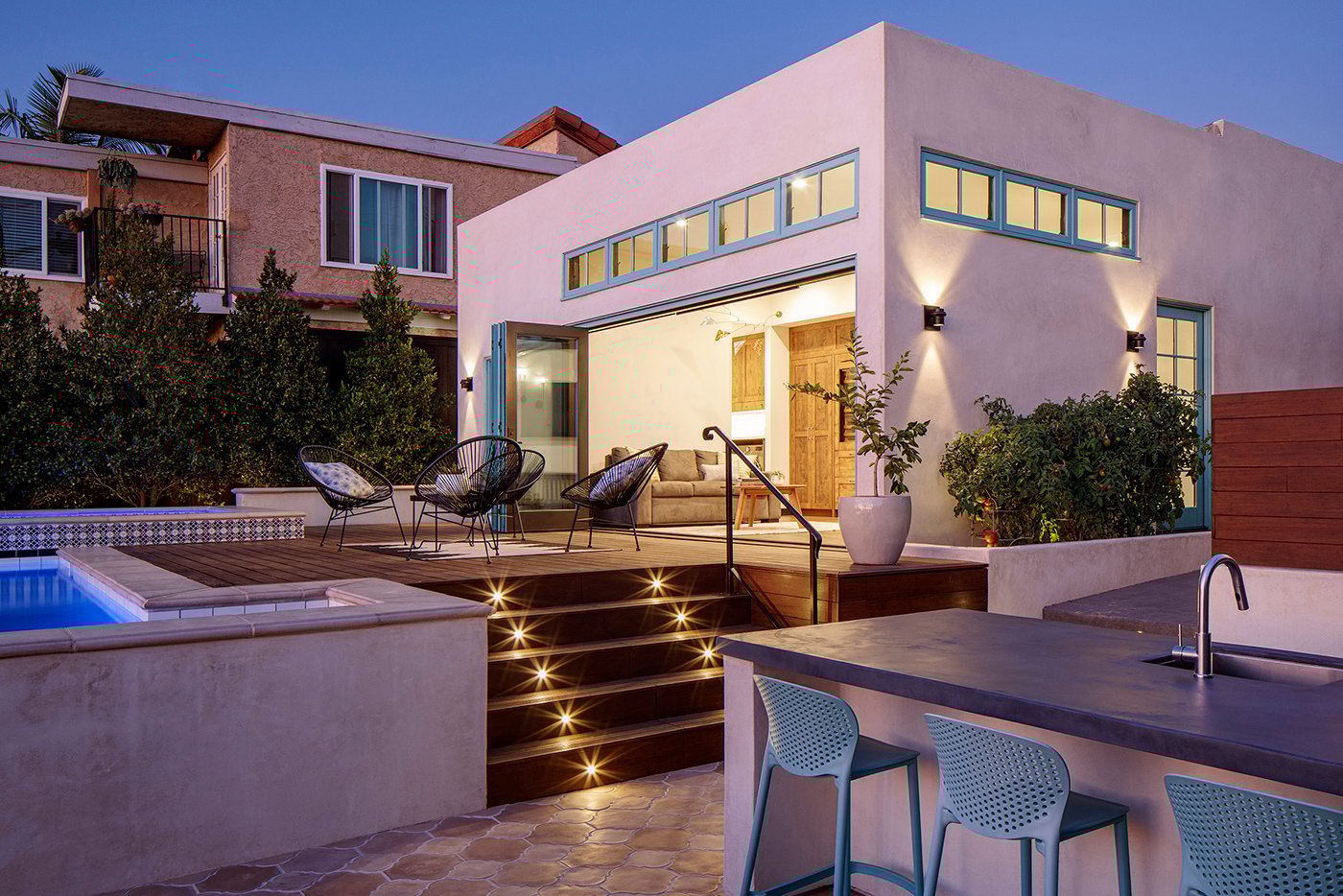 An exterior view of a backyard that’s designed for outdoor living with pool, outdoor kitchen, and more.