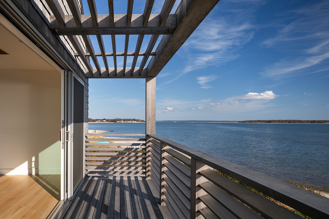 An upper porch with Andersen® E-Series Gliding Patio Doors and views of the ocean.