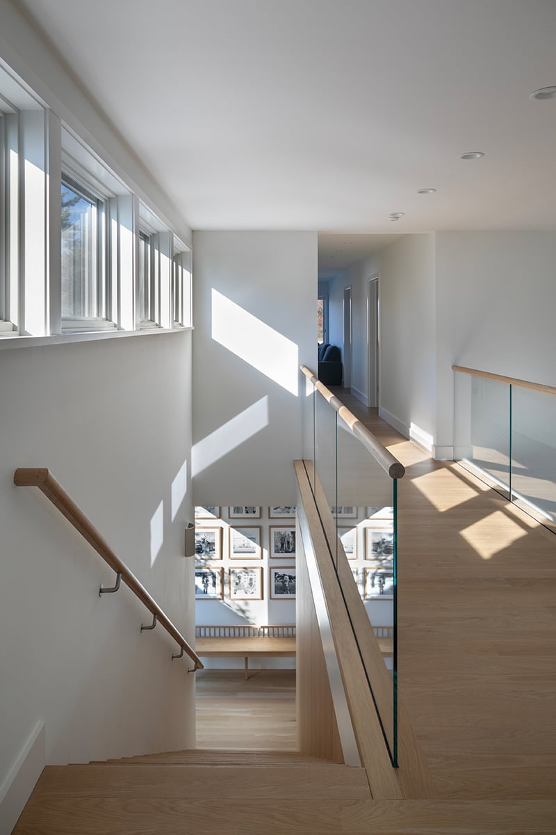 A shot from the top of a stairwell with a hallway and windows letting in natural light.