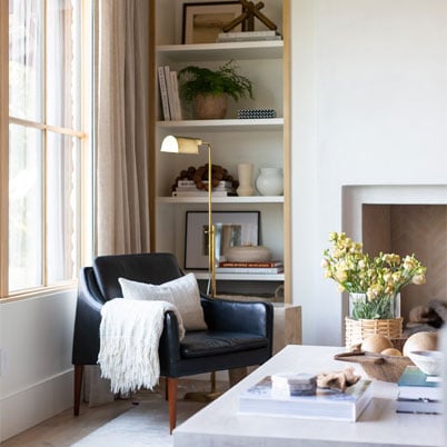 corner of livingroom with black modern chair and andersen e series light wood framed window with panes