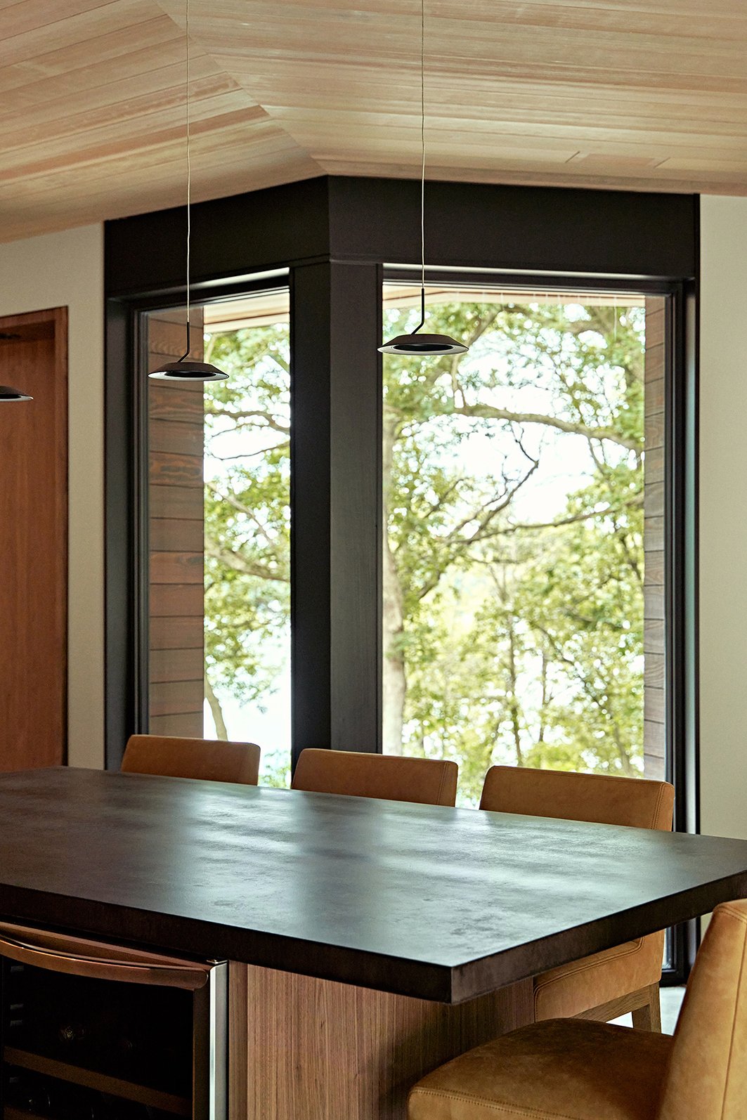A kitchen where two floor-to-ceiling Andersen E-Series Picture Windows on either side of a bend provide views of a lake