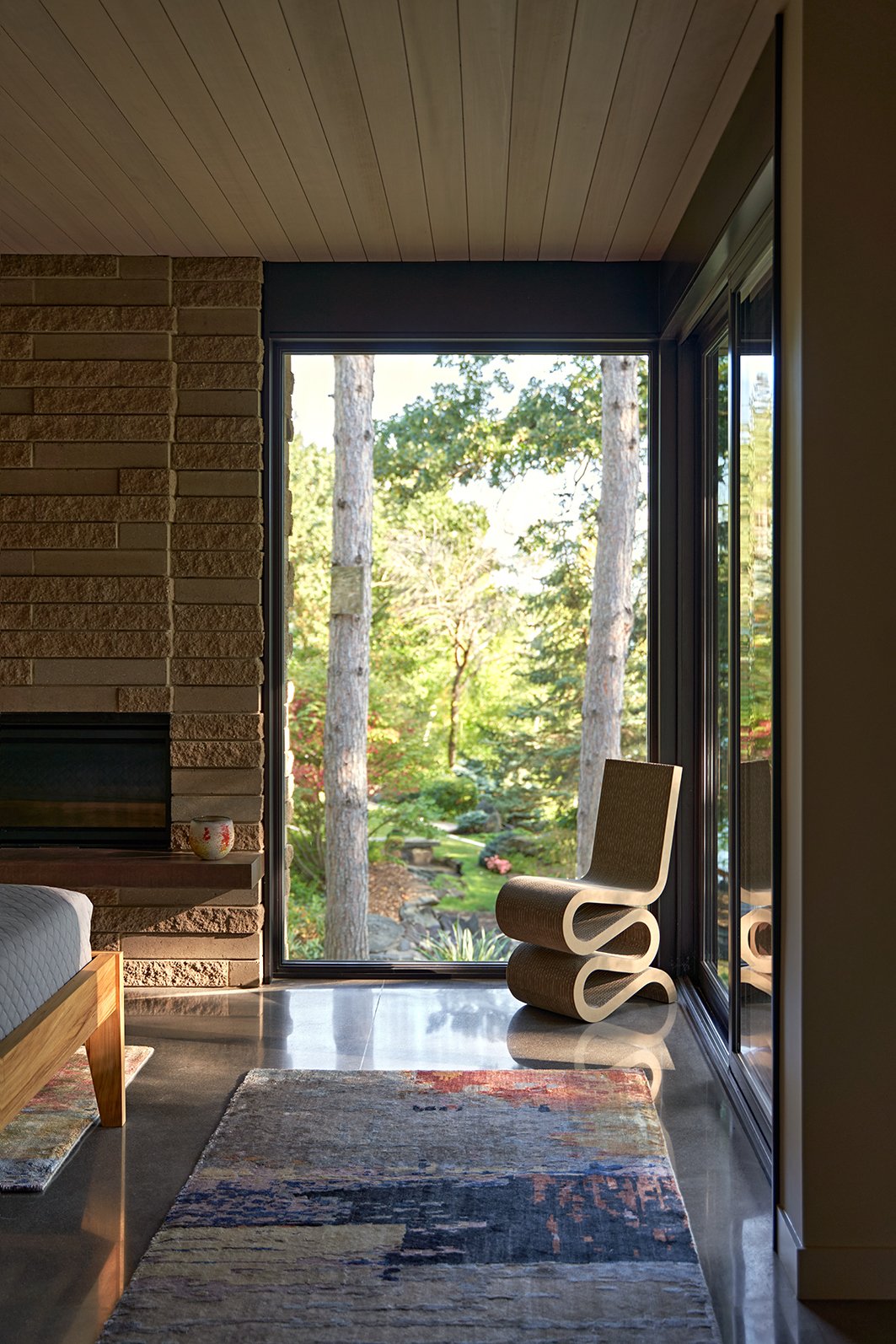 A bedroom with polished concrete floors, a fireplace, and floor-to-ceiling glass.
