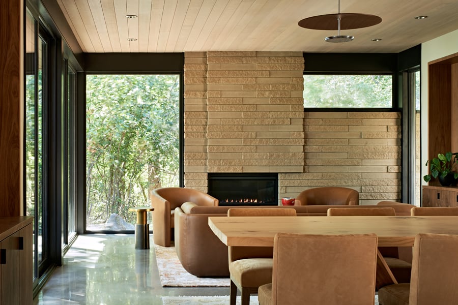 An open-concept dining and living room with floor-to-ceiling Andersen® E-Series Gliding Patio Doors and E-Series Picture Windows.
