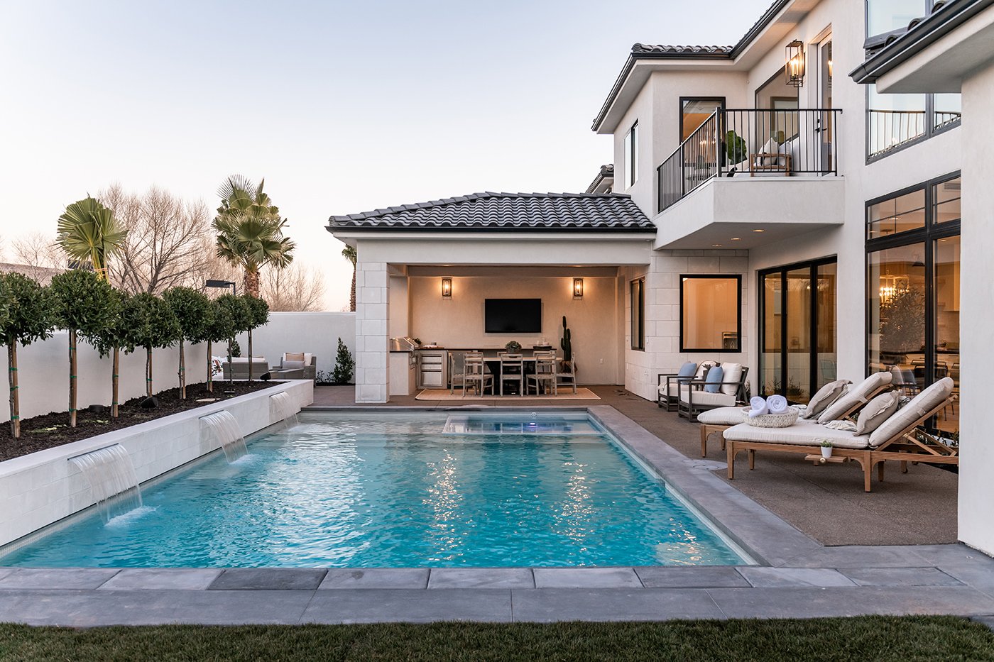 A contemporary luxury home in Utah with a pool, outdoor dining area, and large Andersen 100 Series black windows and an Andersen Aluminum Multi-Slide Door.