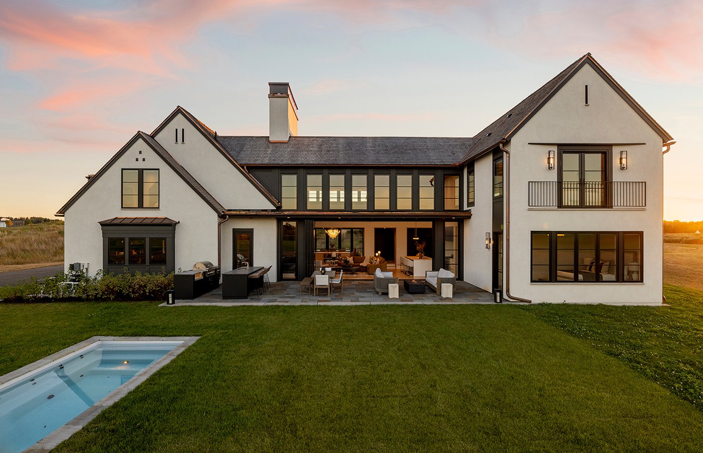 The back of the home has lots of large openings, an outdoor kitchen, and swimming pool.