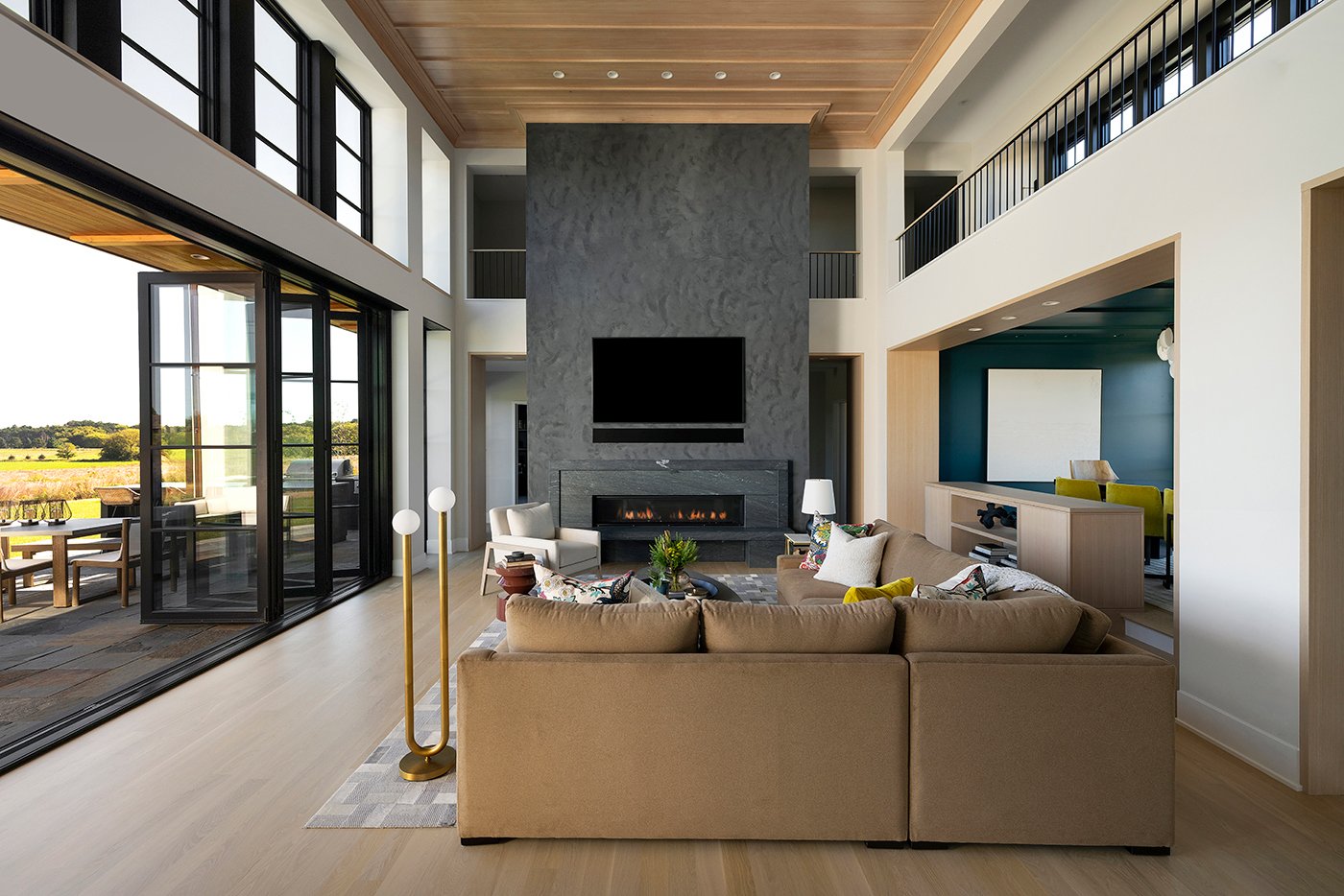 A two-story open concept living room with an open Folding Outswing Door connecting to a patio outside.