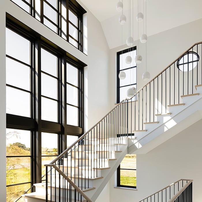 A stair flooded with natural light through the two-story window unit.