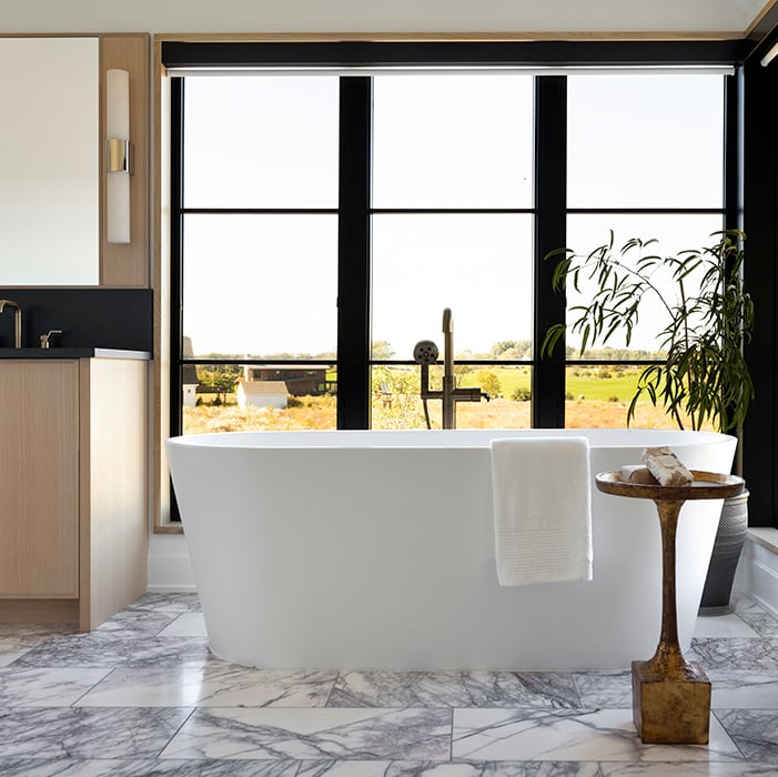 A bathroom with marble floors and Andersen 400 Series windows offering a floor-to-ceiling view.