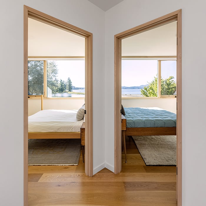 A shot into adjacent bedrooms displaying waterfront views through picture and casement windows.