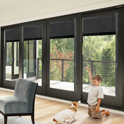 boy playing with dog in front of andersen patio doors with between the blinds