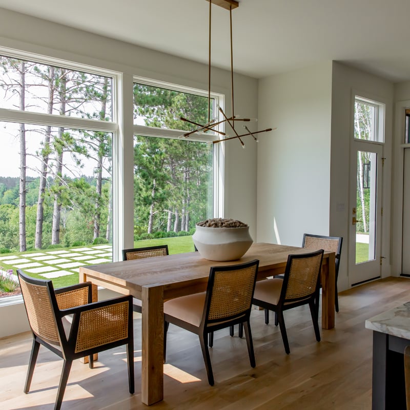 Cozy dining room with 400 Series picture and transom windows overlooking pretty backyard
