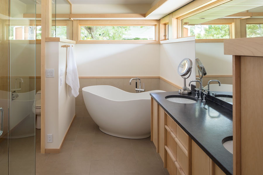 A bathroom with a soaking tub and high awning windows above.