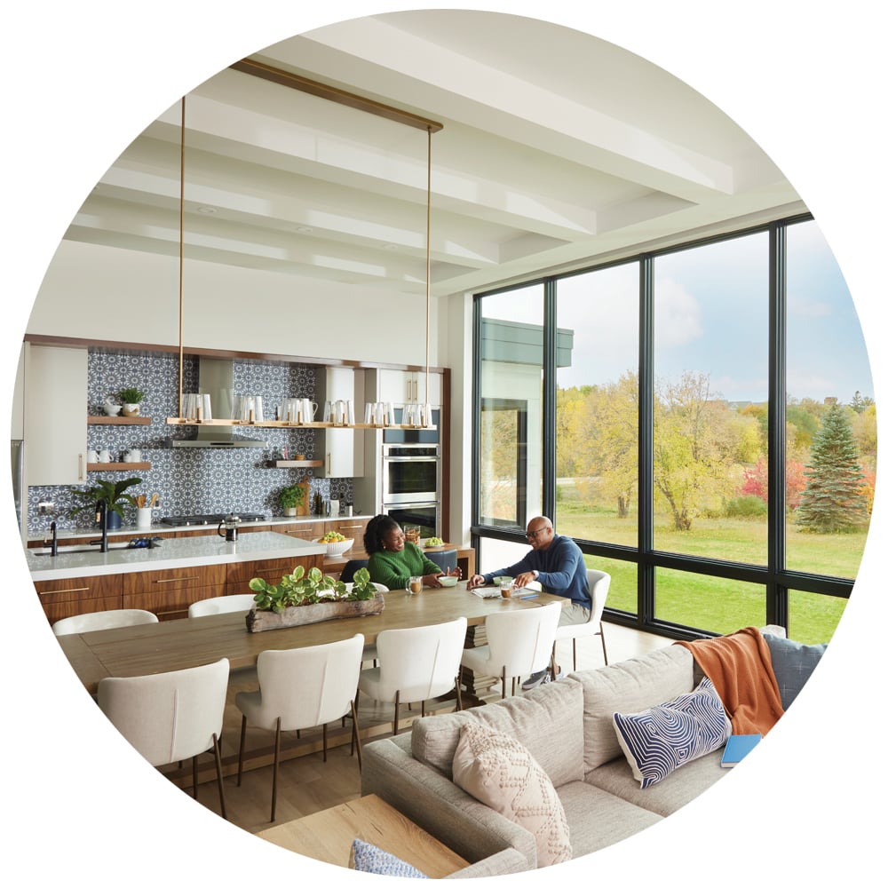 Couple enjoying a meal in an open floor plan kitchen/dining room with floor-to-ceiling windows