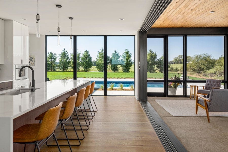 A kitchen and porch with floor-to-ceiling windows facing a backyard swimming pool.