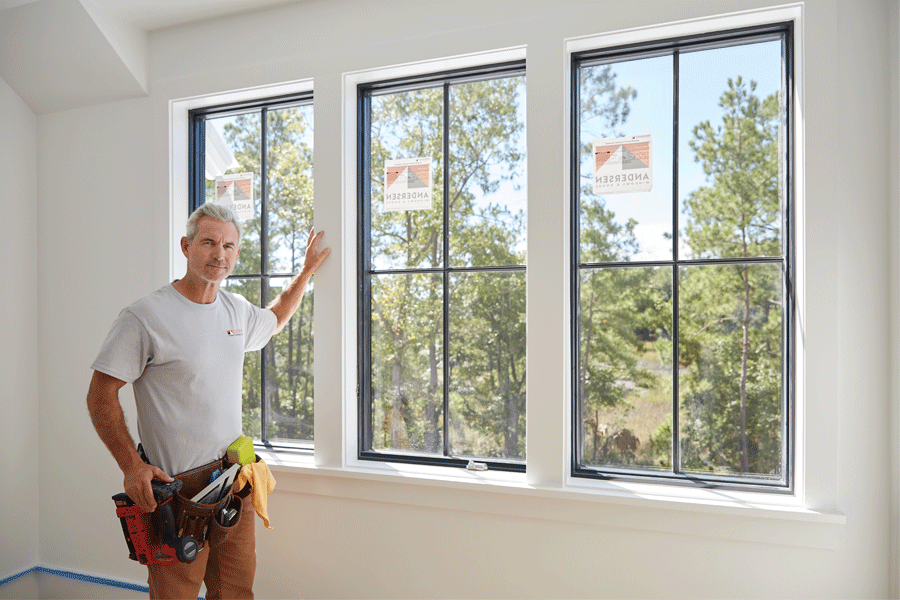 A contractor stands next to a bank of newly installed windows.