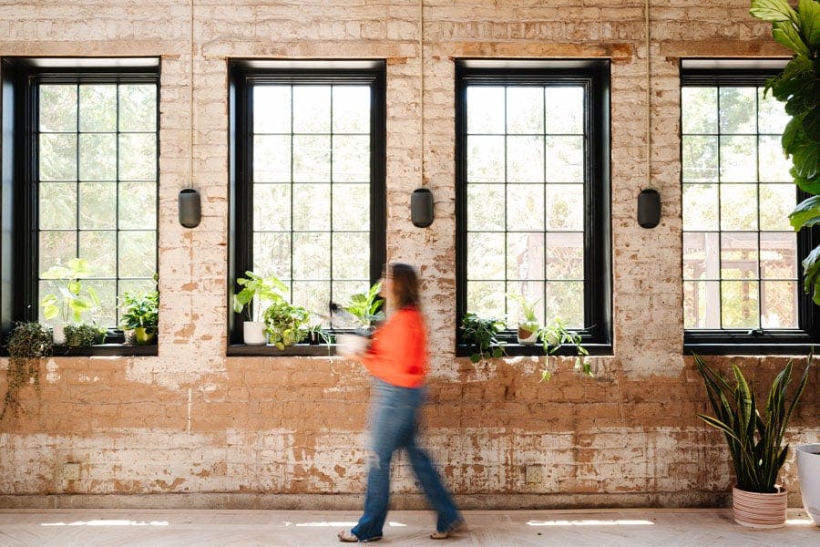 A row of four black windows with colonial grilles in a historic home with exposed brick walls.