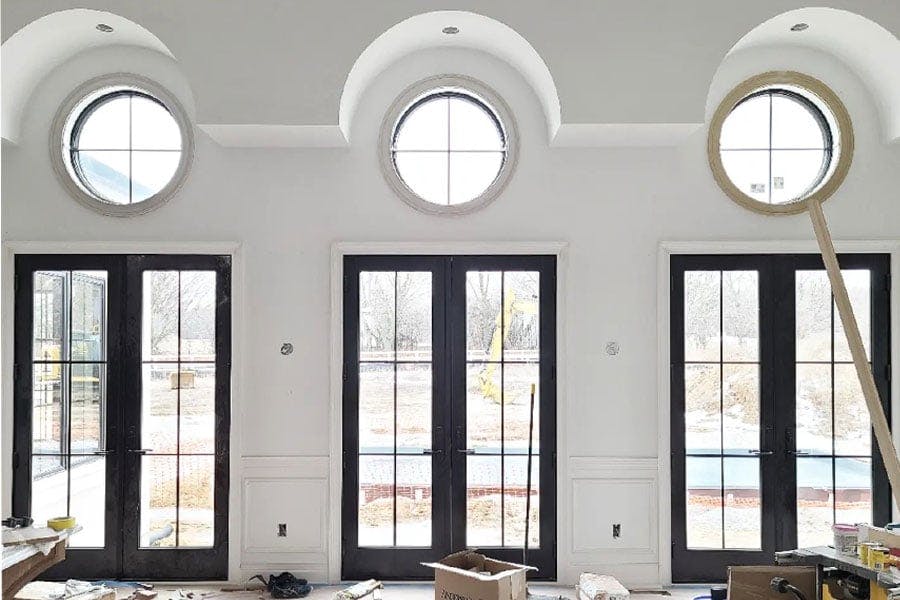 A set of three Andersen A-Series french doors with circle windows above face a soon-to-be constructed patio