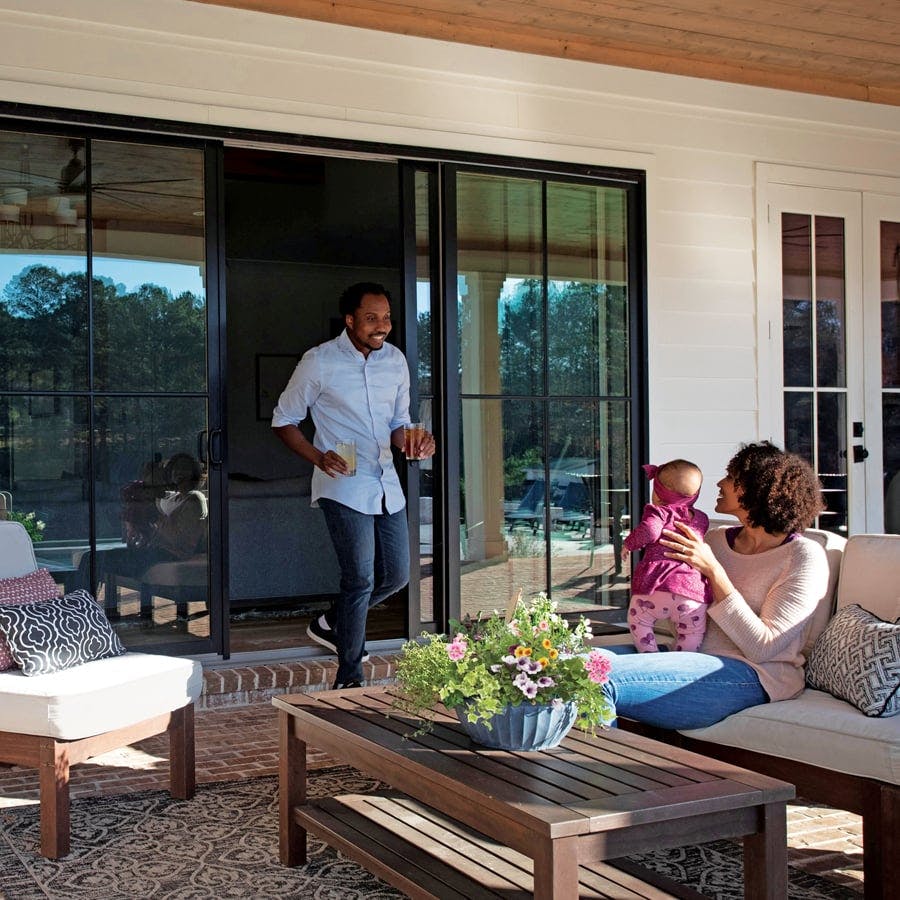 family sitting on patio of home with andersen gliding patio doors