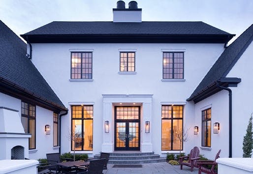 white two story tudor design house with black andersen frame windows with colonial grilles