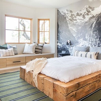 bedroom with wood platform bed and earth mural on wall, andersen e series light wood framed windows