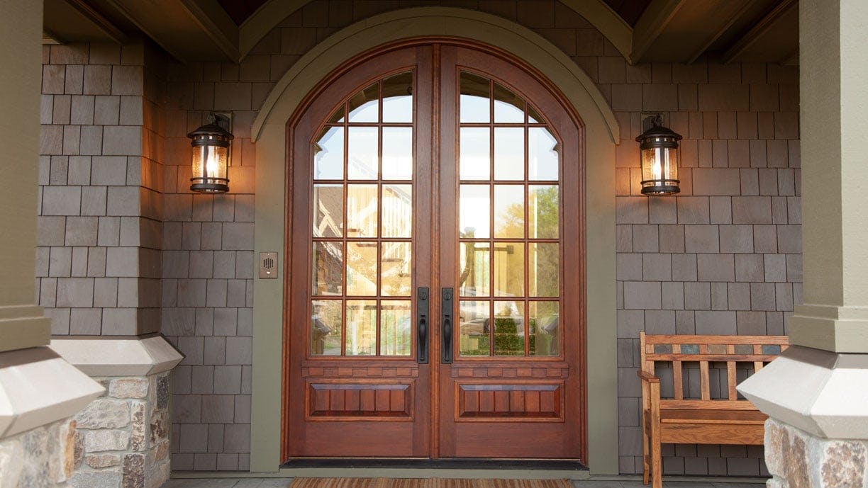 exterior of home with a brown entry door with round top and grid windows