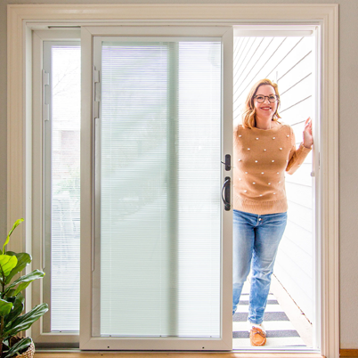 woman walking through andersen patio doors with blinds between the glass