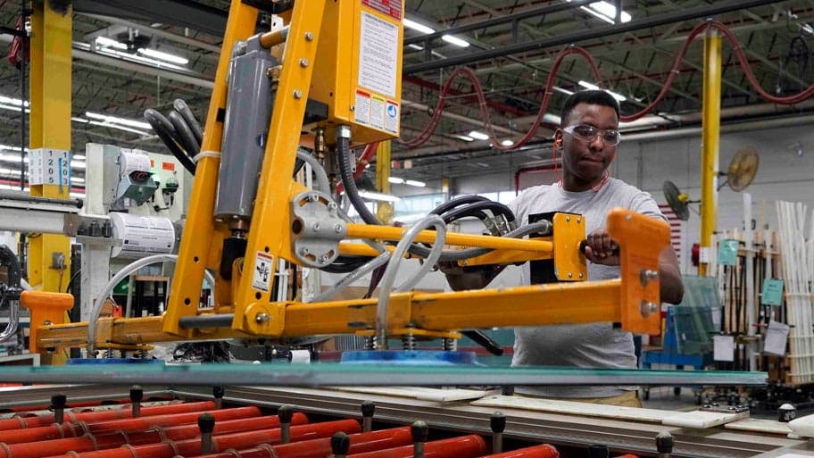 Employee in factory using machine to move glass with safety glasses on